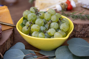 Buffet table is ready with charcuterie board items such as bowls of grapes for the wedding reception guests