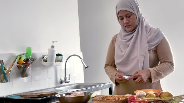 Asian muslim woman peeling, cutting and slicing onion and garlic. Preparing marinade for chicken meat