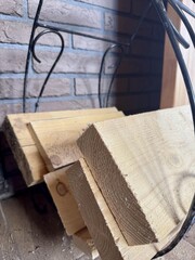 Cut wooden planks stacked together with metal frame near a brick wall indoors