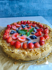 homemade fruit tart with creamy filling topped with fresh strawberries honeysuckle berries and mint...