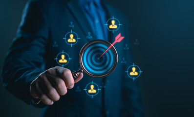 Businessman holding magnifying glass targeting specific audience or customer group, representing marketing strategy, customer segmentation, lead generation, recruitment process and business focus.