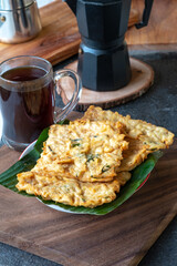  Tempe Mendoan, is served on a banana leaf alongside a cup of hot black coffee. This rustic, close-up shot captures the simple pleasure of a traditional meal