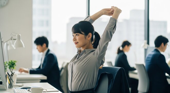 リフレッシュタイム：デスクワークの合間に軽くストレッチをする日本人女性社員