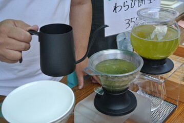 A shop owner brewing green tea by hand