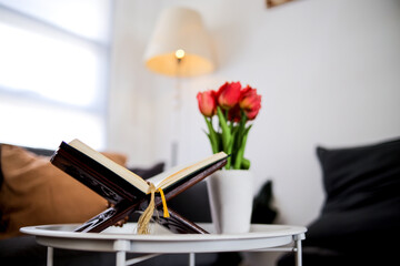Holy Quran On Wooden Stand Next To Vase Of Red Tulips In Modern Living Room Setting