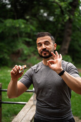 Strong muscular man eating protein bar and gesturing with his hand that it is great 