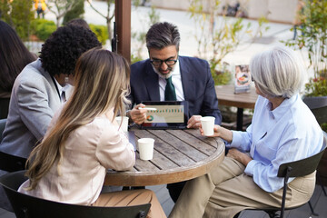 Business team analyzing marketing data on a digital tablet during a coffee break