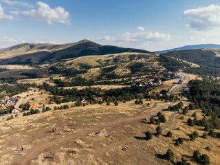 Aerial view of Zlatibor highlands village with forested hills and scattered houses in summer. g.