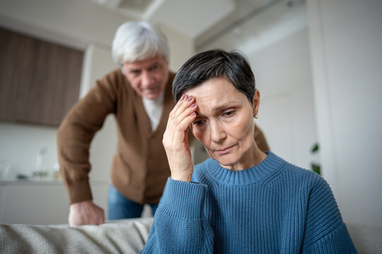 Elderly couple in conflict, man blaming wife while sad woman remains frail and fearful to speak due to abusive partner. Hysterical narcissistic husband, emotional manipulation, toxic relationship