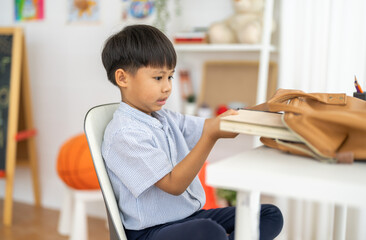 Asian boy getting ready for back to school preparation organizing books and stationery into school...