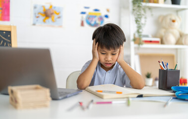 Asian boy stressed homework studying with hands on head, tired expression shows school pressure...