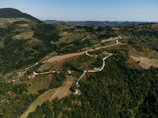 Aerial view of Zlatibor highlands village with forested hills and scattered houses in summer. g.