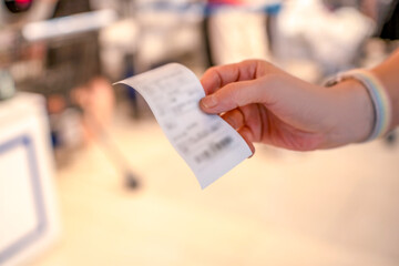 Hand holding a printed receipt in an indoor setting
