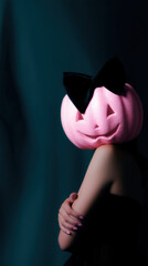 Pink pumpkin with black bow creates unique halloween vibe, featuring mysterious person in dark elegant lighting and soft shadows
