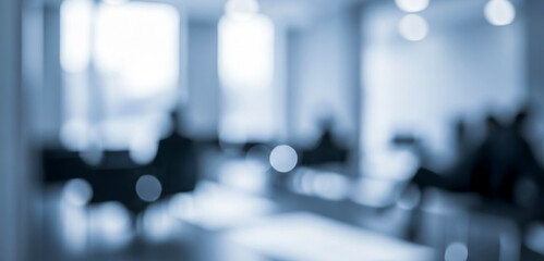 Obraz premium Blurred office interior with people sitting at desks in a blue tone, giving a modern corporate atmosphere that suggests teamwork, productivity, and creative collaboration.