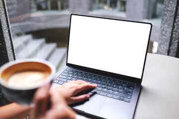 Mockup image of a woman working and typing on laptop computer with blank white desktop screen while...