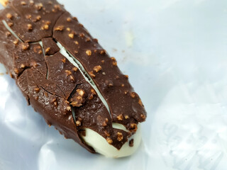 Pieces of chocolate bark with small crunchy bits are scattered on a creamy ice cream surface.