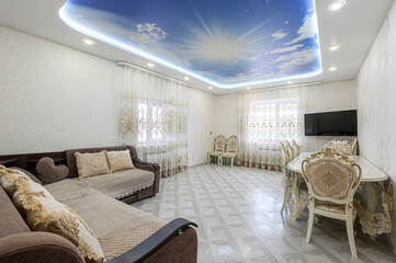Cozy living room featuring a cloud-painted ceiling, comfortable brown sofa, patterned curtains, and an ornate dining set