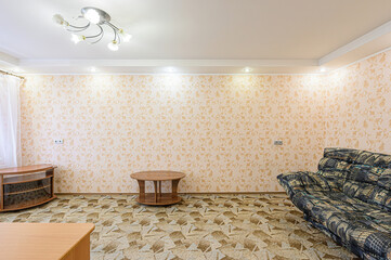 room with patterned wallpaper, patterned floor, and a patterned sofa. There's a round table and a...