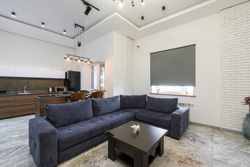 Modern living room and kitchen space. Features a navy blue sectional sofa, dark wood coffee table, and sleek kitchen with island seating