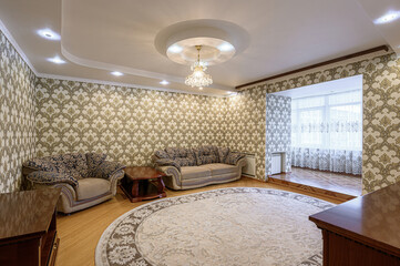 lavish living room features patterned wallpaper, plush seating, a round rug, and an elegant chandelier, creating a classic, upscale ambiance