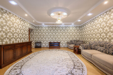 well-lit room features patterned wallpaper, hardwood floors, and a large oval rug. Furniture...