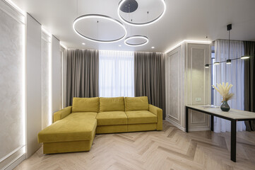 modern living room with a mustard sofa, unique lighting, and herringbone wood floors