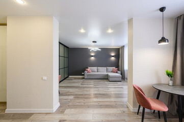 Modern living space: gray sofa, wooden floors, dark accent wall, and stylish decor. Sleek, contemporary design with soft lighting