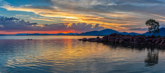 landscape over water at the lake dam at sunset with hills and rocks, blue sky with clouds, Africa...
