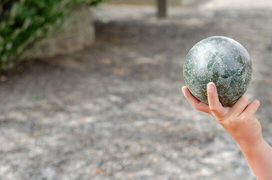 A family plays the fun outdoor lawn game bocce ball in an Italian village, an outdoor activity that is similar to outdoor bowling.