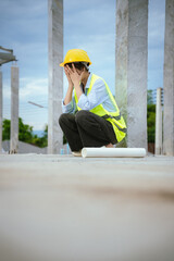 Female construction worker in hard hat and safety vest looking stressed, highlighting workplace...