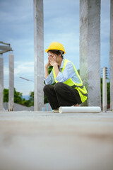 Female construction worker in hard hat and safety vest looking stressed, highlighting workplace...