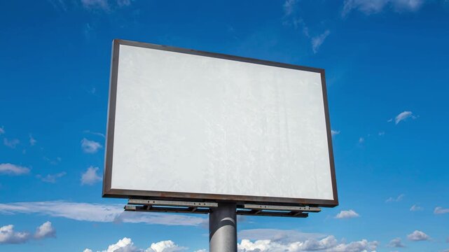 Blank billboard sign on pole against bright blue sky with scattered white clouds perfect for outdoor