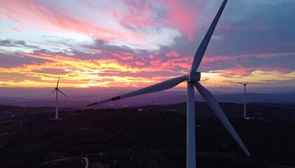 Rotating Wind Turbine Blades at Sunset Over Rolling Hills