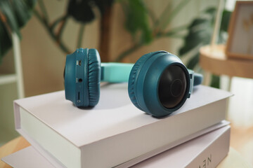 Headphones resting on stacked books near a plant