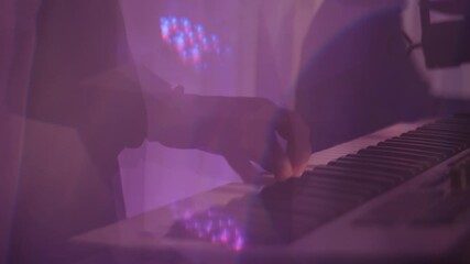 Close-up of a man's hands playing synthesizer keys in a nightclub in flashing neon light. Musicians play live music in a disco club. - Powered by Adobe
