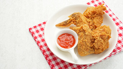 Crispy fried chicken wings served with chilli sauce on white plate
