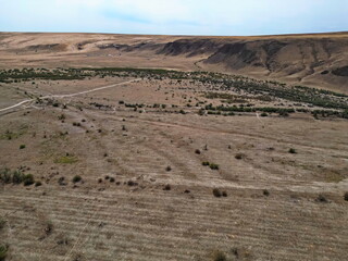 A rolling rocky valley with sand and rocks. The view from the drone.