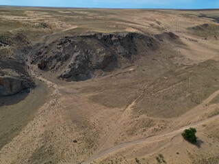 A rolling rocky valley with sand and rocks. The view from the drone.