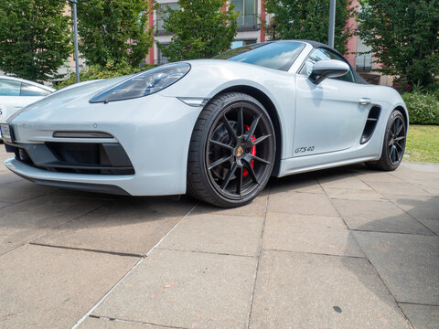 White Porsche 718 Boxster GTS 4.0 parked on pavement, highlighting sleek sports car profile with premium styling against urban backdrop