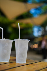 Two plastic cup with cool water on a wooden table