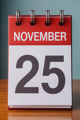 November 25th Calendar Page Displayed on a Wooden Surface with a Soft Blue Background in Studio