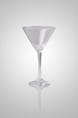 Empty martini glass isolated on light gray background, elegant transparent cocktail glassware for drinks and bar design.