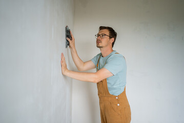 Dedicated construction worker expertly smooths a wall using a hand tool. Focused on achieving a...