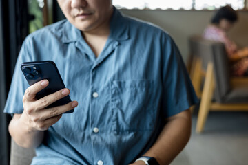 Man is using a smartphone while sitting inside a cafe