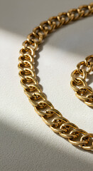 Obraz premium Photo of Golden Chain Jewelry on a Textured Surface with Shadow and Light
