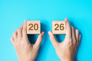 hand holding wooden cube block with 2026 text on blue background. Resolution, plan, review, goal, start and New Year holiday concepts