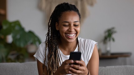 happy african millennial woman holding smart phone watching social media video content smiling young black teen gen z girl using funny mobile app laughing playing game chatting on cell at home no log
