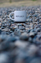 Close-up of  a reflection-themed cup outdoors, symbolizing mindfulness, slowing down, and mental...