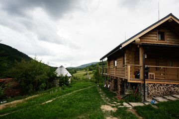 Rustic wooden cabin in a lush green countryside with looming cloudy skies